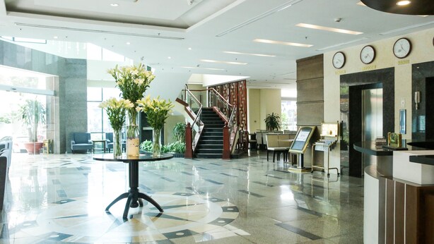 Un hall d’entrée avec un comptoir de réception, un escalier et un arrangement floral sur une table.