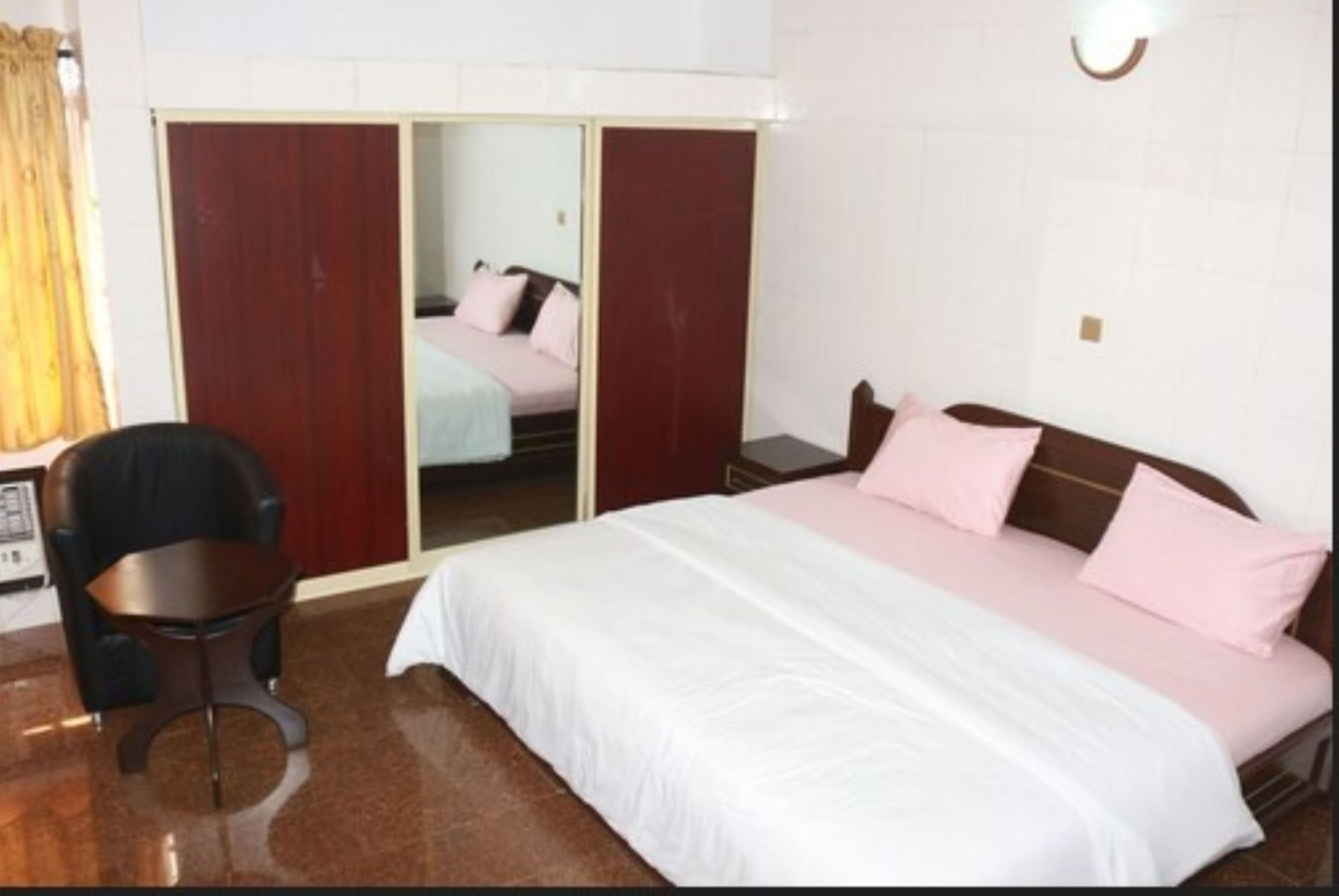 A bedroom with a bed, a chair, a desk, and a wardrobe.