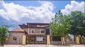 A two-story building with a brick facade, a flat roof, and a gated entrance. - Cute Villa Hotel and Suites (Uyo)