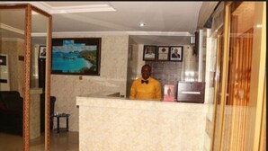 A reception area with a marble counter, framed artwork on the wall, and a framed picture above the counter. - Cute Villa Hotel and Suites (Uyo)