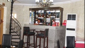 A bar area with a marble counter, two bar stools, a staircase, and a refrigerator. - Cute Villa Hotel and Suites (Uyo)