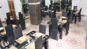 A dining area with multiple tables and chairs, a central pillar, and a patterned floor. - Cute Villa Hotel and Suites (Uyo)