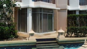 Un hotel moderno de varios pisos con piscina, con balcones y ventanas amplias.