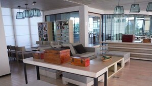 Una sala moderna con una mesa central, sofás y una estantería.