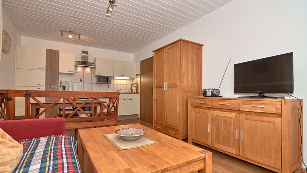 A modern kitchen with wooden cabinets, a dining table, and a television.