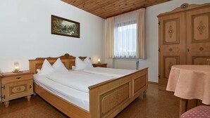 A bedroom with a wooden bed, nightstands, a table, and a wardrobe.