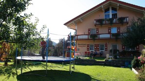 A trampoline in a grassy area with a building in the background.