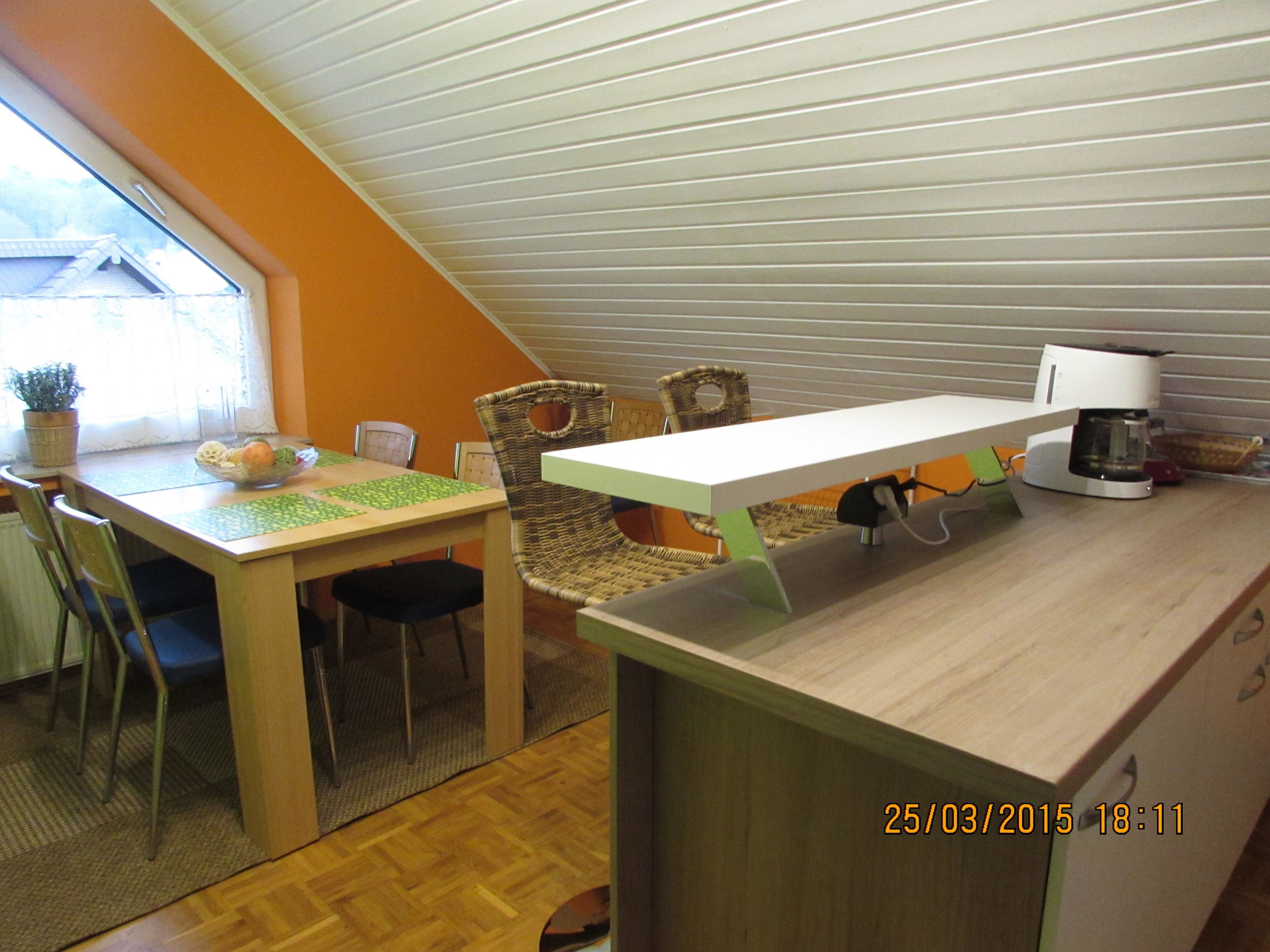 Un comedor con una mesa de madera, sillas y una cafetera.