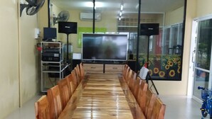 A conference room with a long wooden table, a projector screen, and a small fan on the wall. - Palm Kaew Resort Krabi (Krabi)