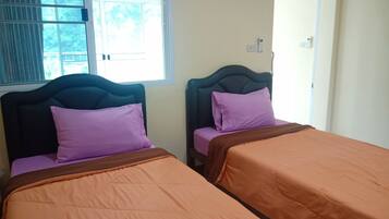 Two single beds with headboards, a window with blinds, and a wall-mounted light fixture.