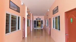 A hallway with doors on both sides, a ceiling light, and a door with a green sign. - Palm Kaew Resort Krabi (Krabi)