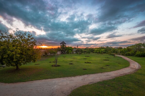 A park with a gazebo, a dirt path, and a sunset in the background.