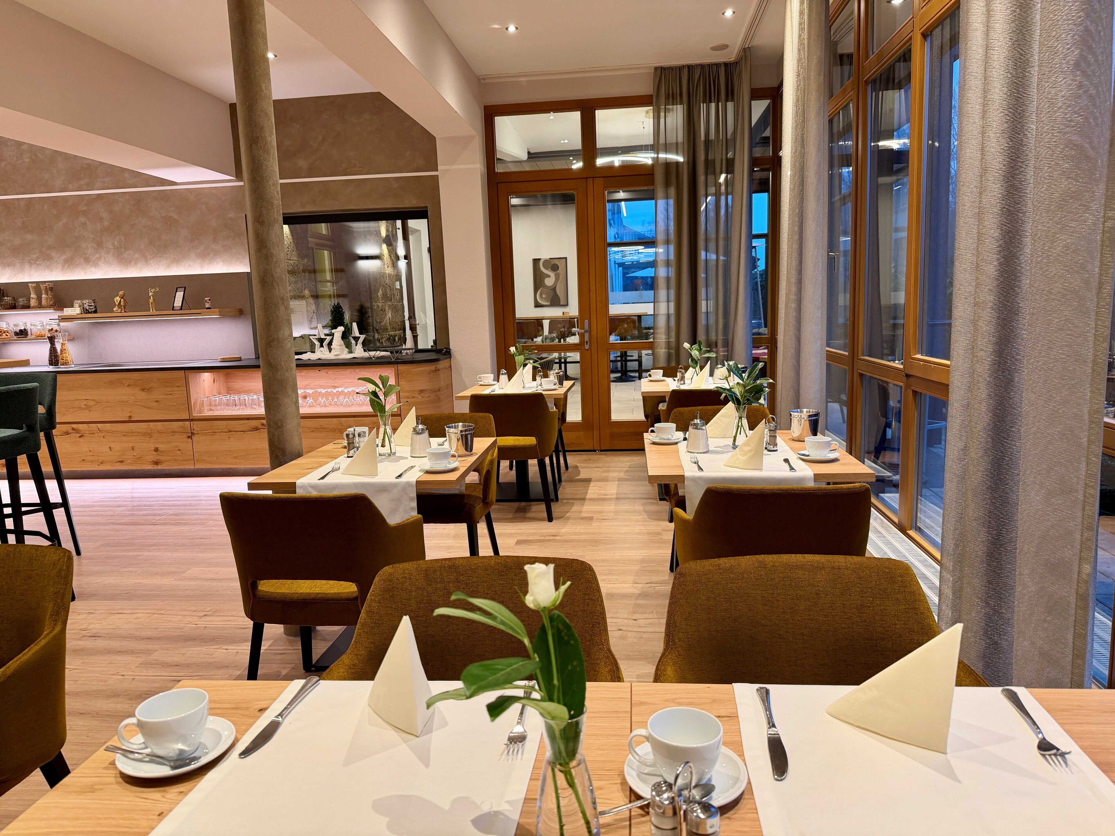 A modern dining area with wooden tables, chairs, and a bar counter.