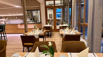 Un espace repas moderne avec des tables et des chaises en bois, ainsi qu’un comptoir de bar.