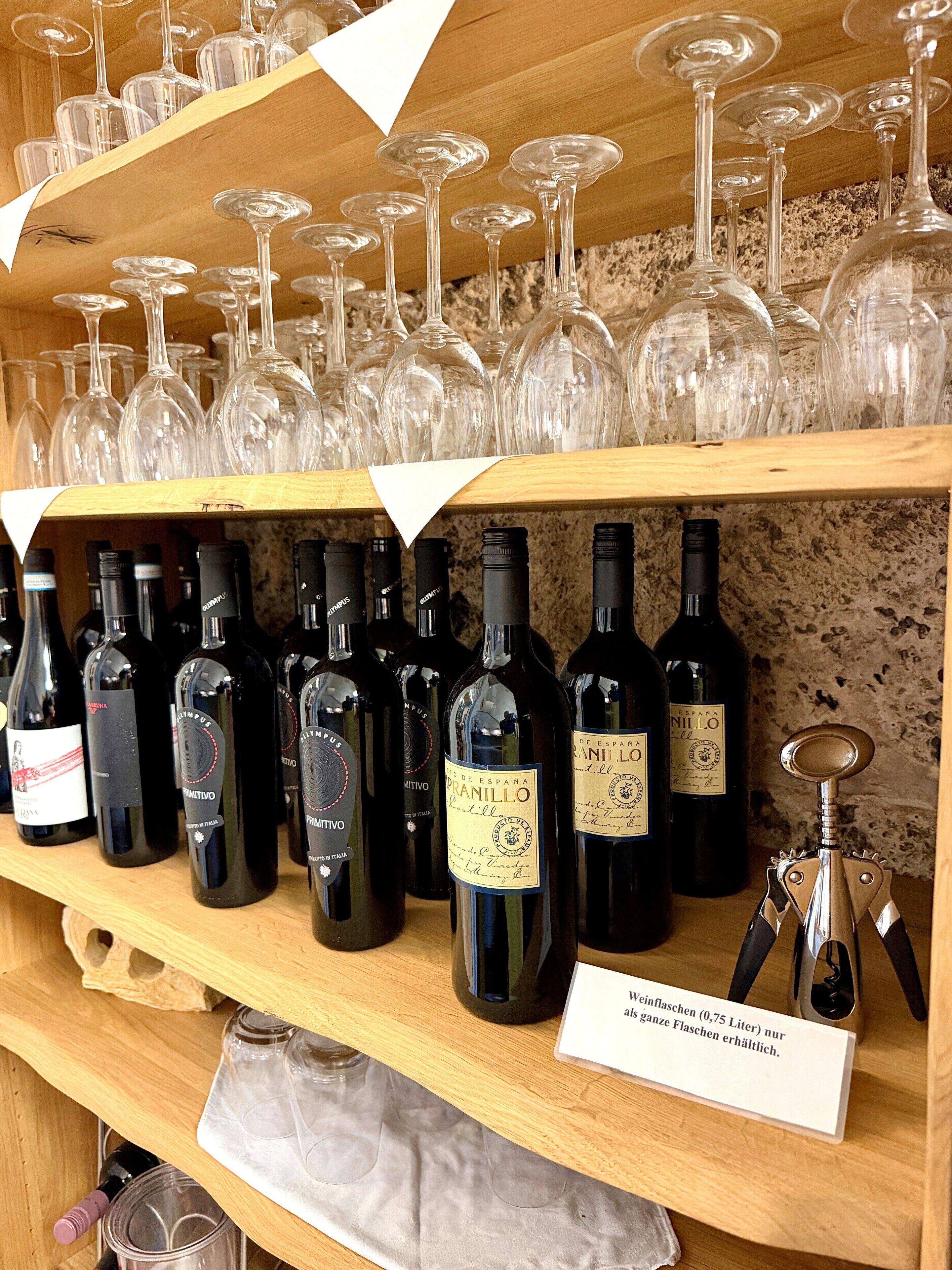 Un meuble à bouteilles contenant différentes bouteilles de vin et des verres.