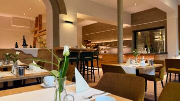 Un interior de restaurante moderno con mesas y sillas de madera, y una zona de bar central.