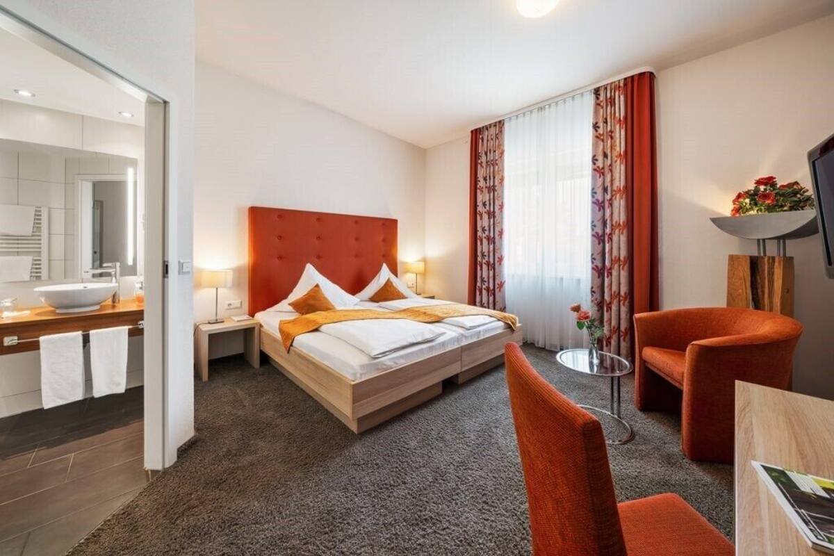 Una habitación de hotel con una cama grande, un escritorio con lavamanos, una silla y un televisor.