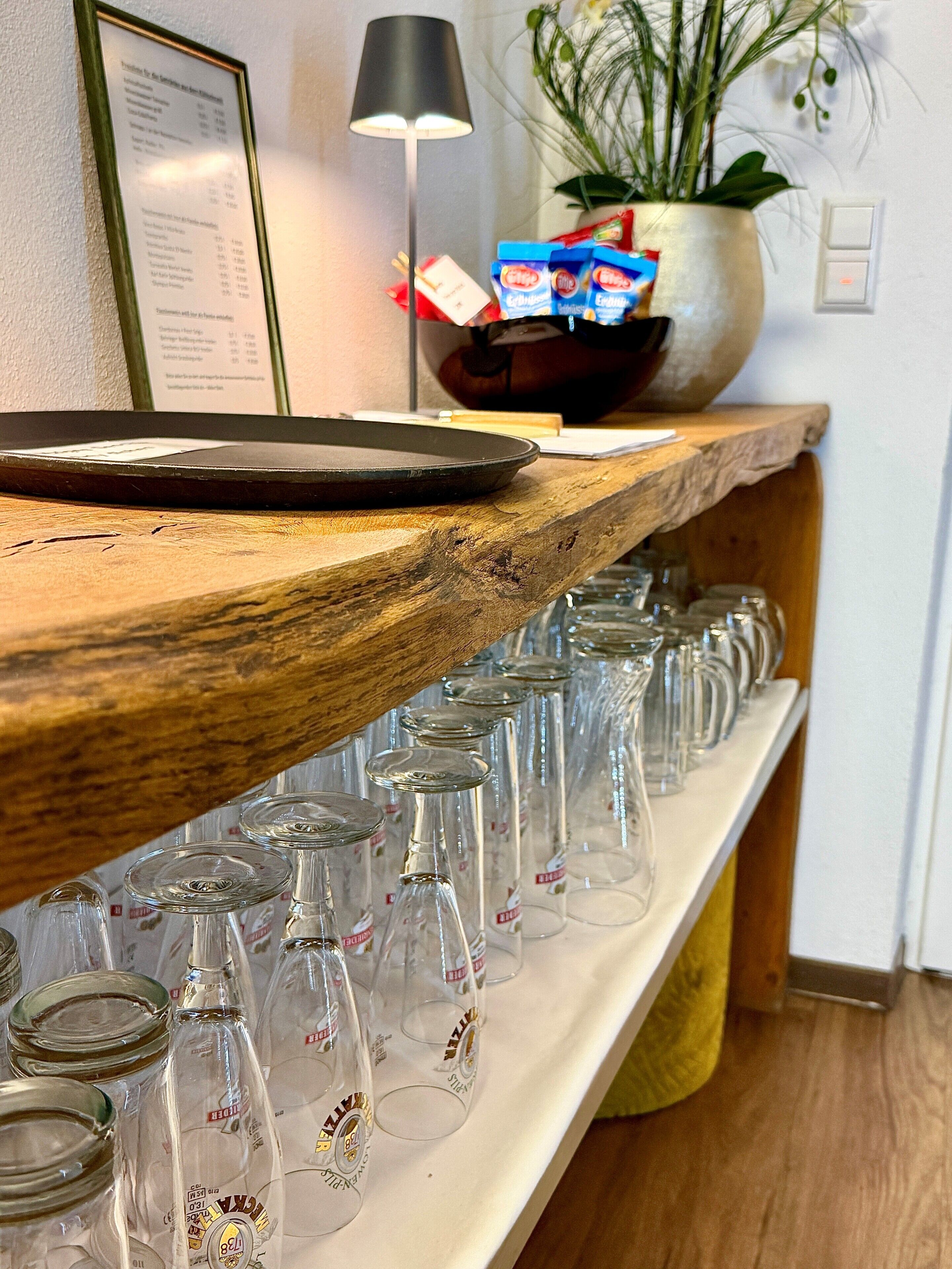 A bar area with a wooden shelf holding glasses and a menu.