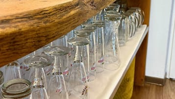A bar area with a wooden shelf holding glasses and a menu.