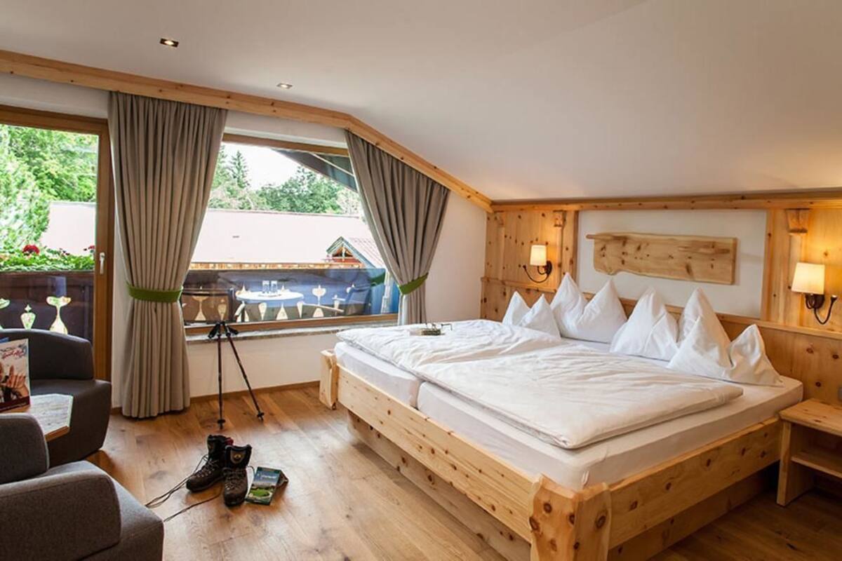 A wooden-framed bedroom with a large bed, a desk, and a window with curtains.