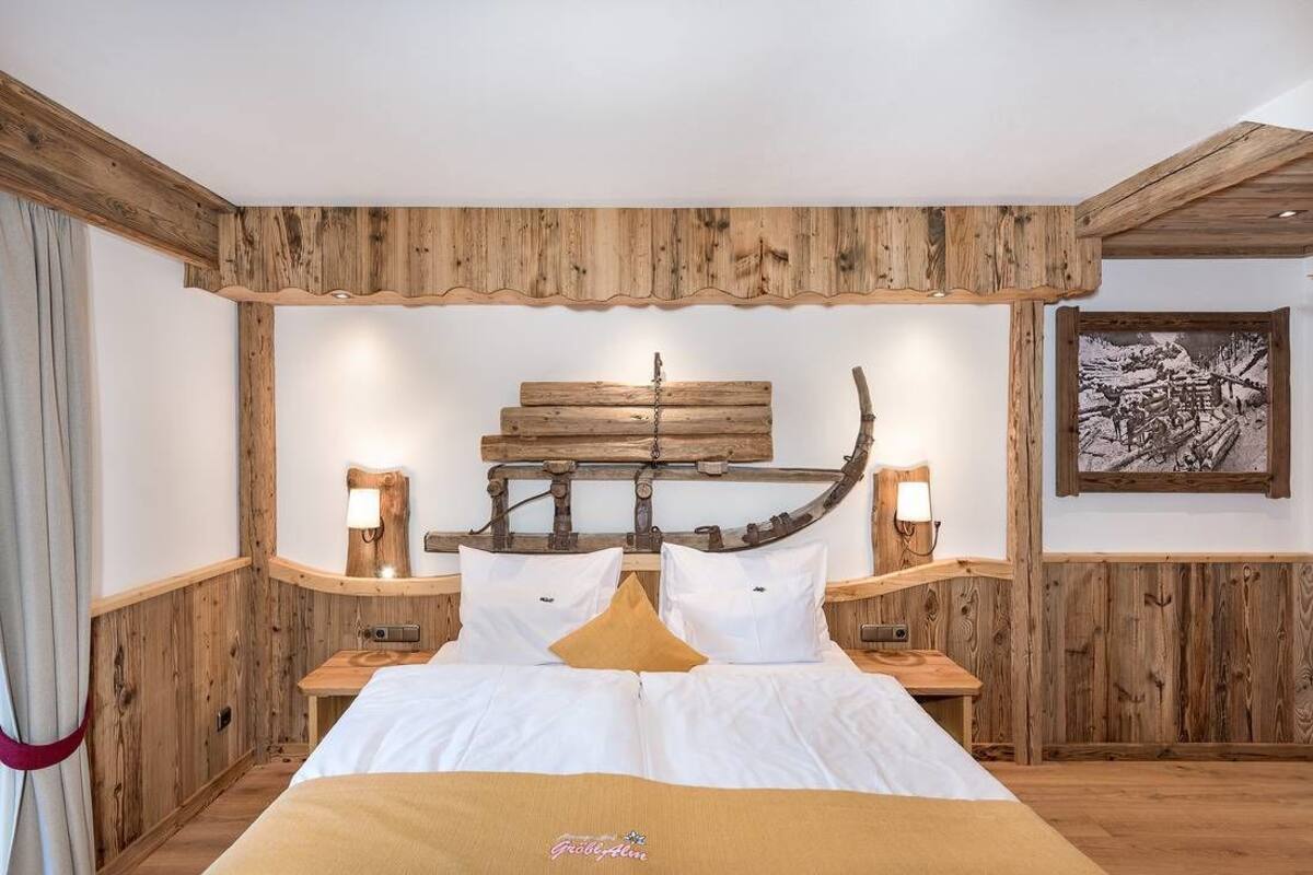 A wooden-framed bedroom with a bed, two bedside tables, and a wall-mounted light fixture.