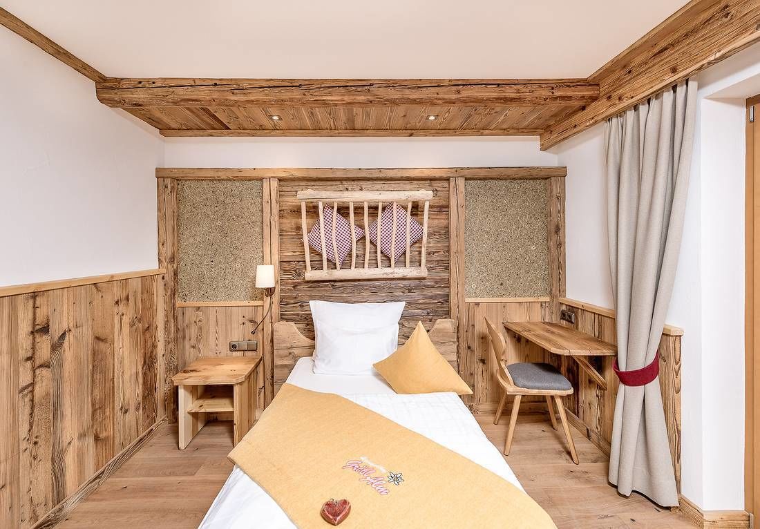 A wooden room with a bed, a desk, and a chair.