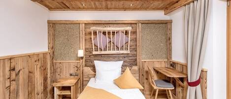 A wooden room with a bed, a desk, and a chair.
