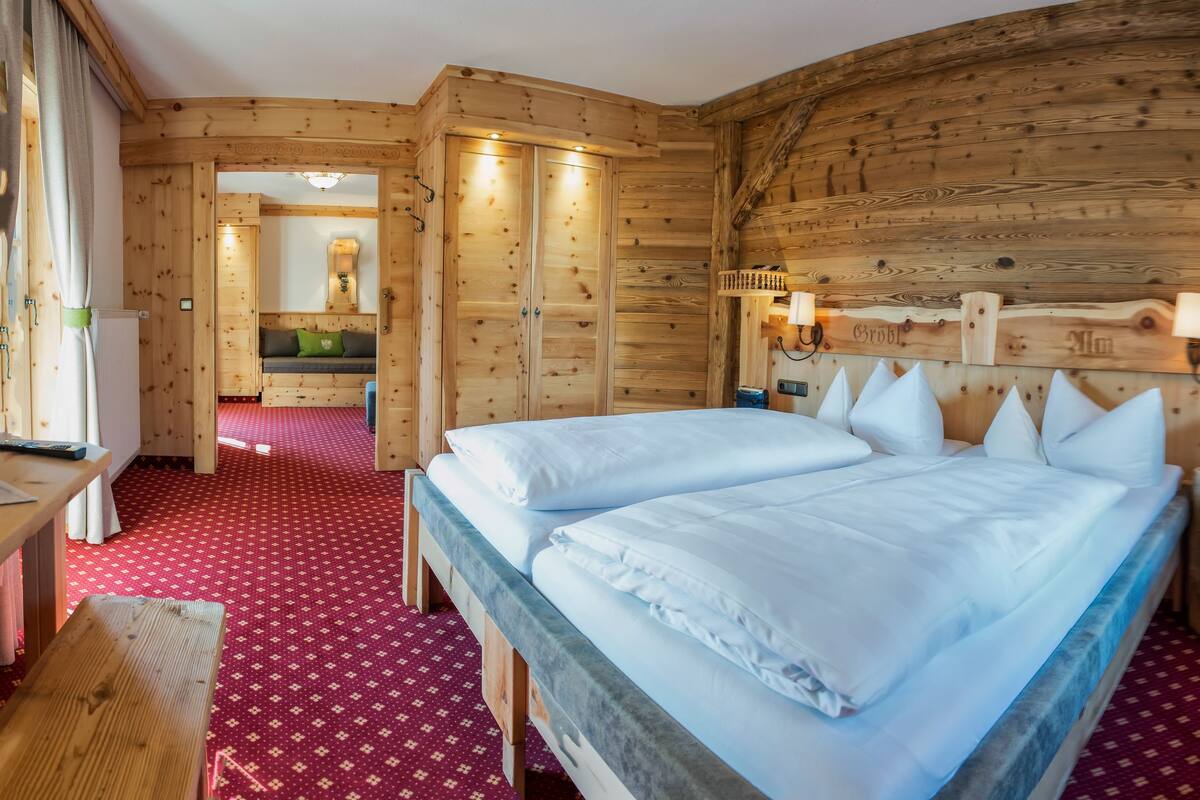A wooden room with a bed, a bench, and a small stool.