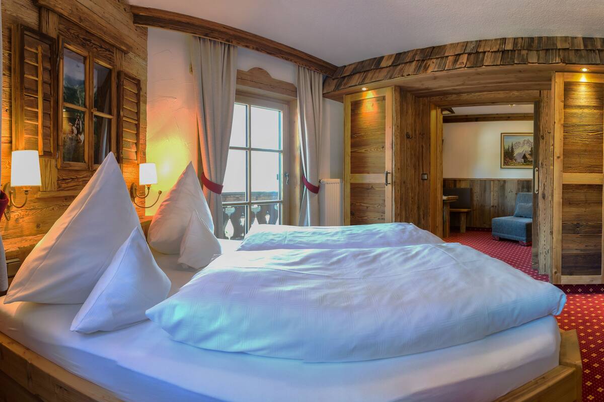 A hotel room with a large bed, wooden walls, a television, and a red carpeted floor.
