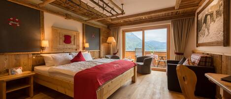A wooden-floored room with a bed, a desk, and a chair.