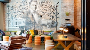 A modern living room with a brick wall mural, a green sofa, leather chairs, and a wooden coffee table.