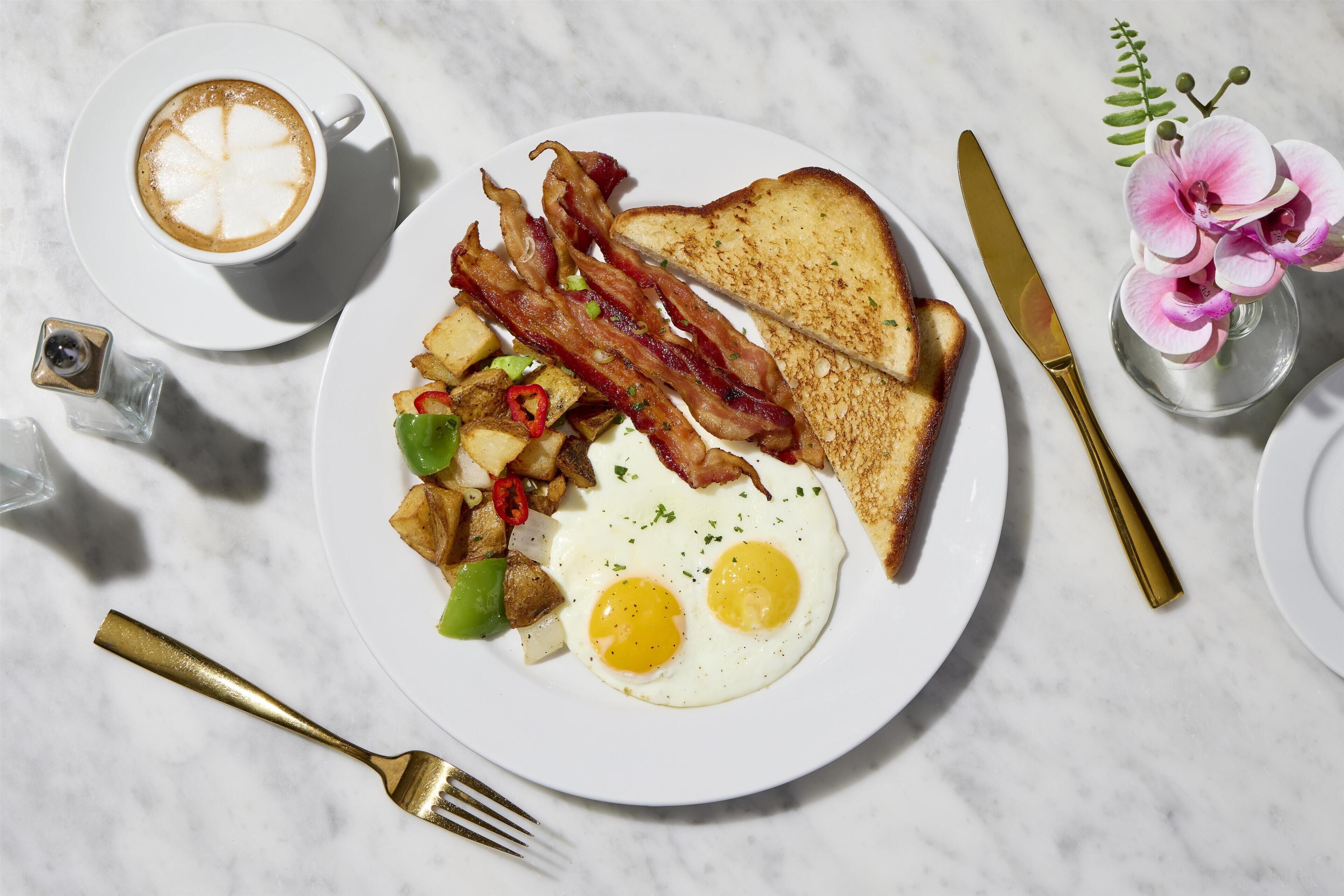 Un plato de desayuno con huevos, tocino, tostadas y papas.