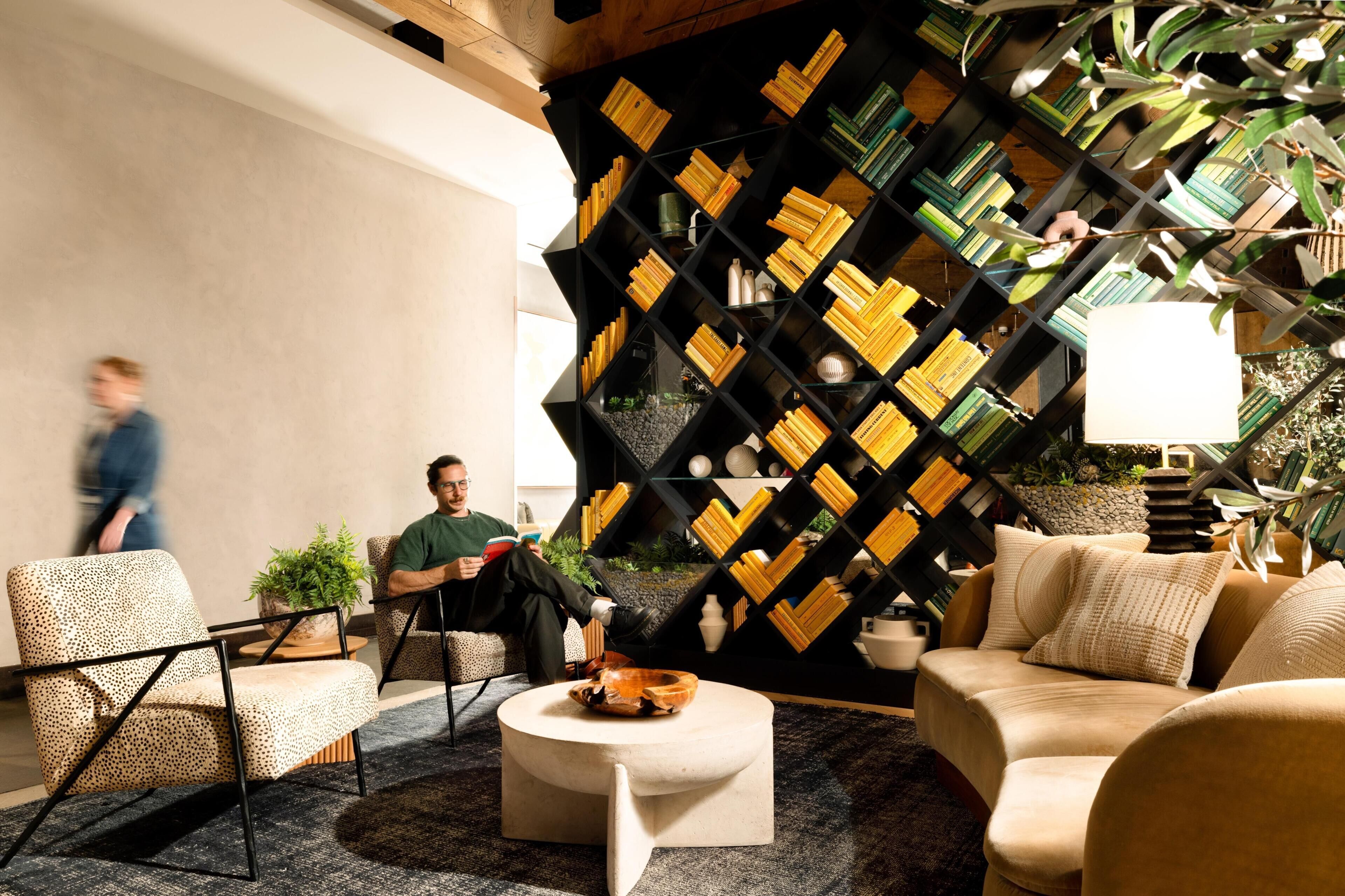 A modern lounge area with a geometric bookshelf, comfortable seating, and a coffee table.