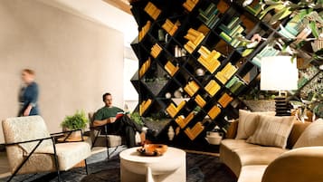 A modern lounge area with a geometric bookshelf, comfortable seating, and a coffee table.
