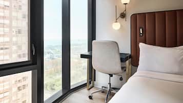 Una habitación de hotel con un ventanal grande, una cama, un escritorio y una silla.