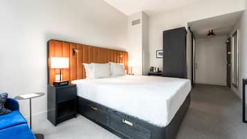 A hotel room with a large bed, bedside tables, a small desk, a chair, and a wardrobe.