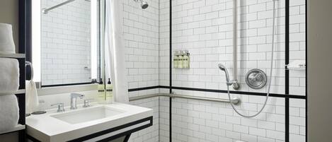 A modern bathroom with a white sink, a mirror, a shower with a handheld showerhead, and a towel rack.