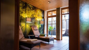 Un espace de détente avec deux chaises longues, une fresque murale et une grande fenêtre.