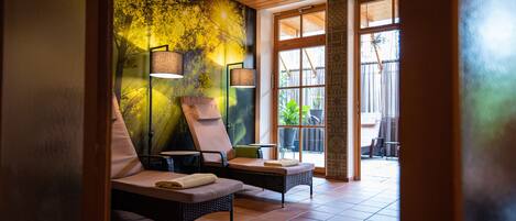 Un área de spa con dos sillones de relax, un mural en la pared y un ventanal grande.