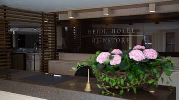 Un área de recepción con diseño moderno, que incluye un mostrador de recepción, un espejo y un letrero que dice "HEIDE HOTEL REINSTORE".