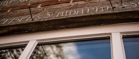 A close-up of a wooden sign with carved text, part of a building's exterior.