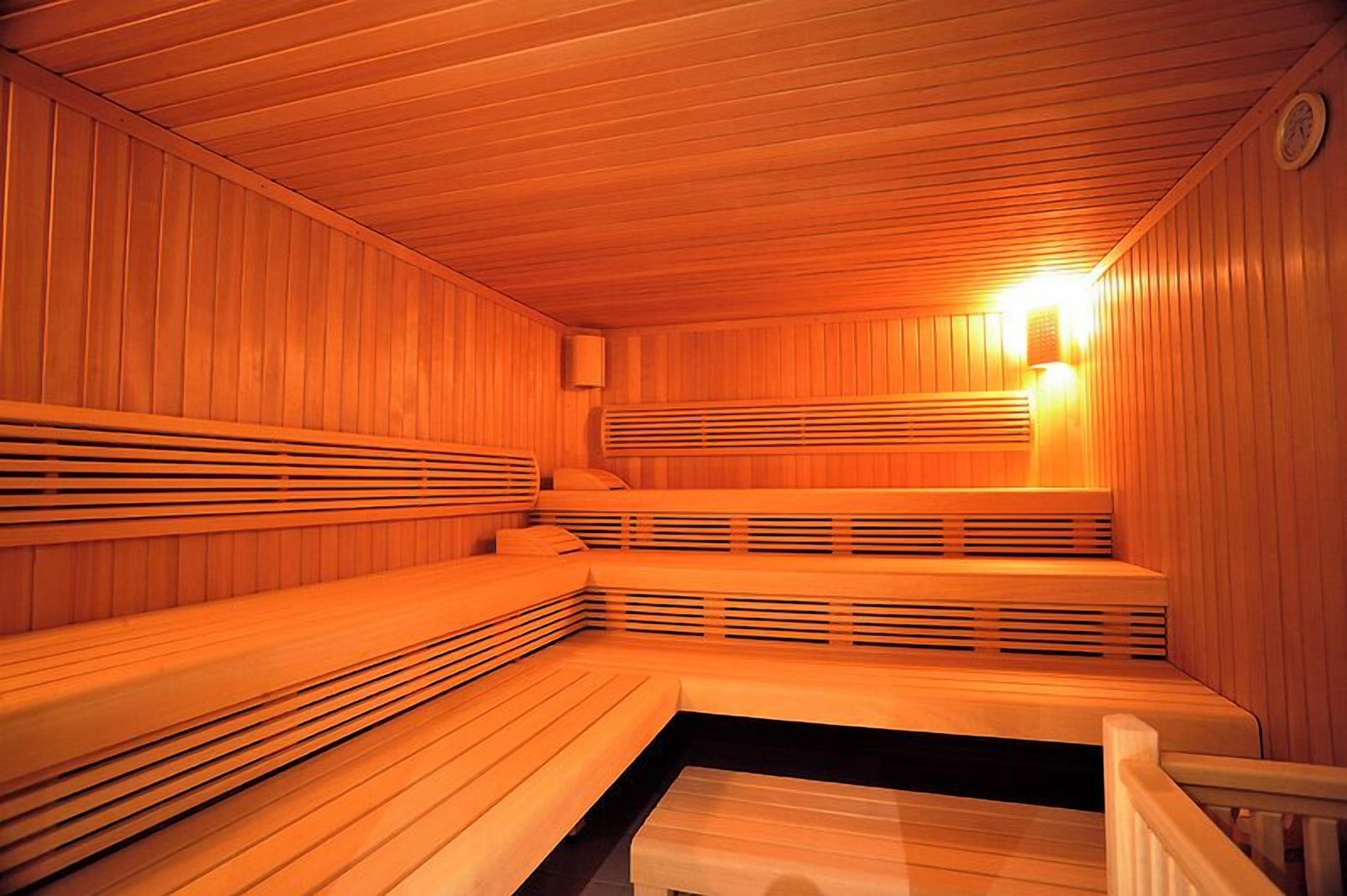 Una sauna con bancos de madera y un banco con asiento negro.