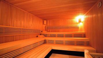Una sauna con bancos de madera y un banco con asiento negro.