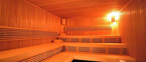 Una sauna con bancos de madera y un banco con asiento negro.