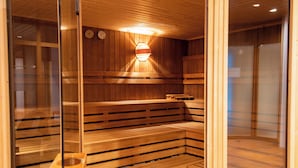 Un sauna en bois, doté de bancs et d’un luminaire fixé au mur.
