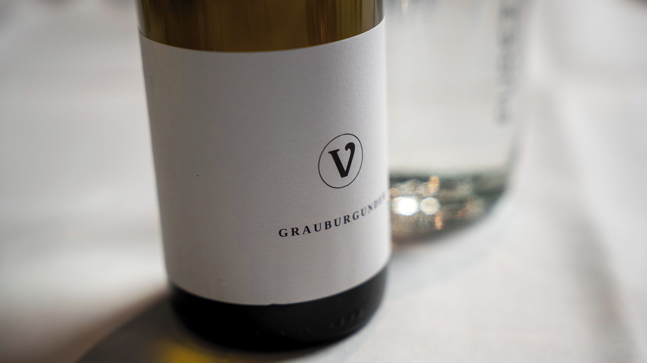 A close-up of a wine bottle label with the text "GRAUBURGUNNEN" and a logo.