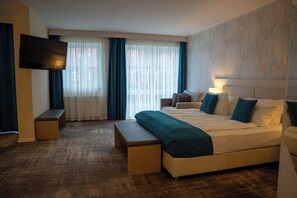 A hotel room with a large bed, a bench, a TV, and a window with curtains. - Heide Hotel Reinstorf (Reinstorf)