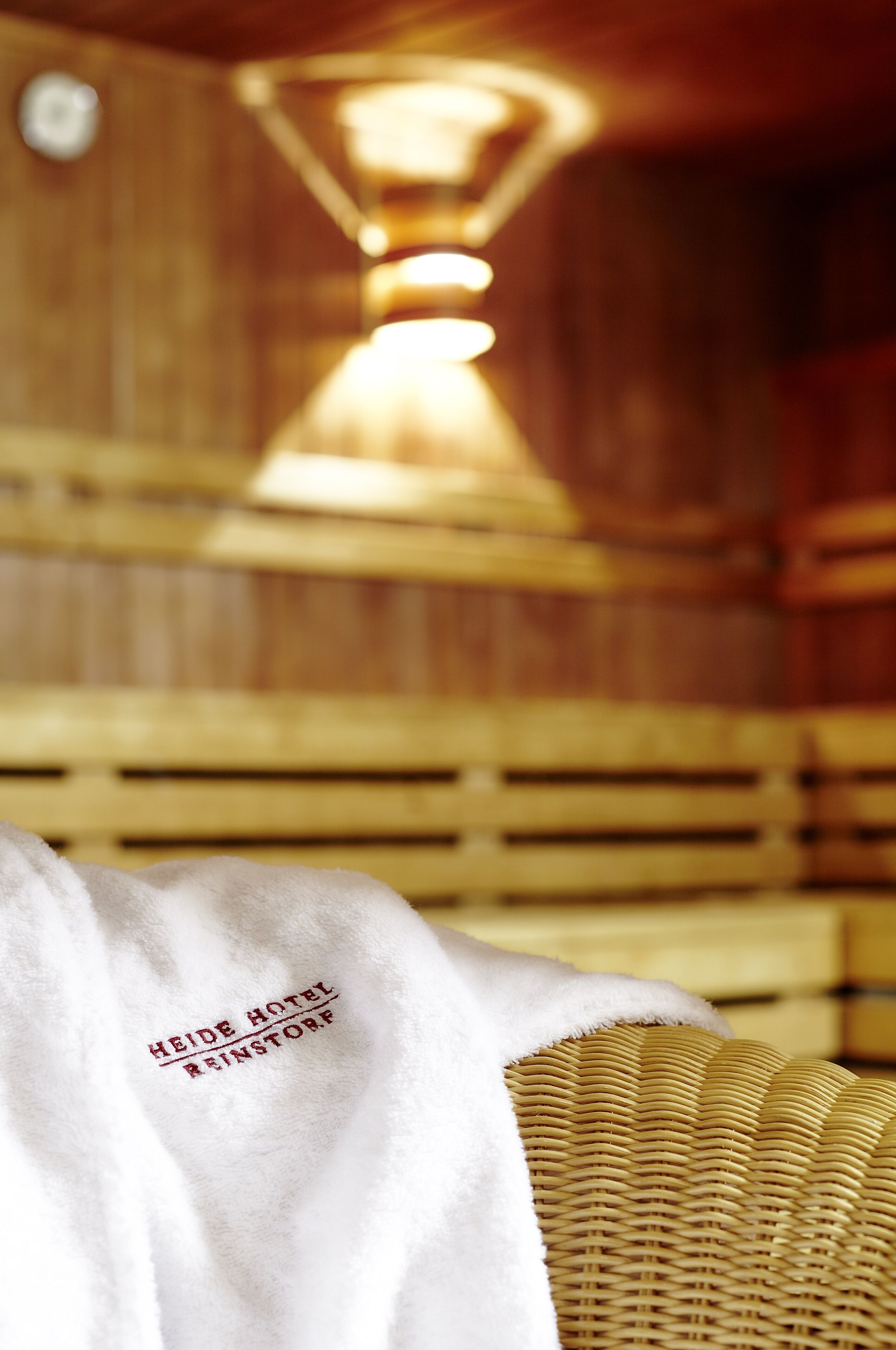 Un interior de madera con una silla tejida y una toalla blanca que dice "Heide Hotel Reinstorf".