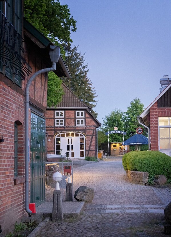 A cobblestone street leading to a traditional building with a sign reading 'Biergarten.' - Heide Hotel Reinstorf (Reinstorf)