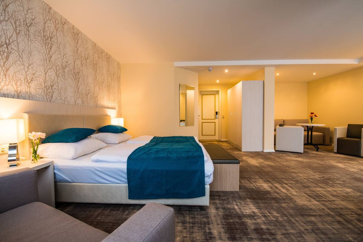 A hotel room with a bed, bedside tables, a desk, and a chair.